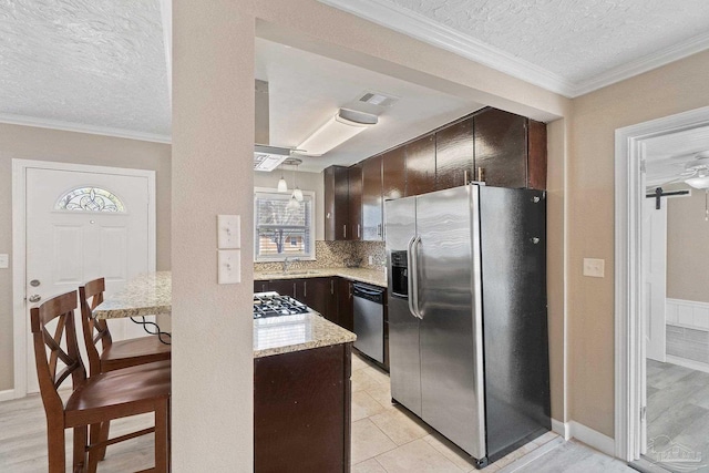 kitchen featuring ornamental molding, dark brown cabinets, appliances with stainless steel finishes, and a textured ceiling