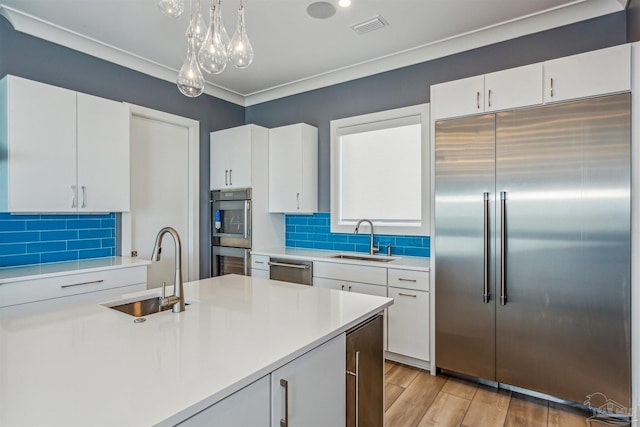 kitchen featuring pendant lighting, appliances with stainless steel finishes, sink, and white cabinets