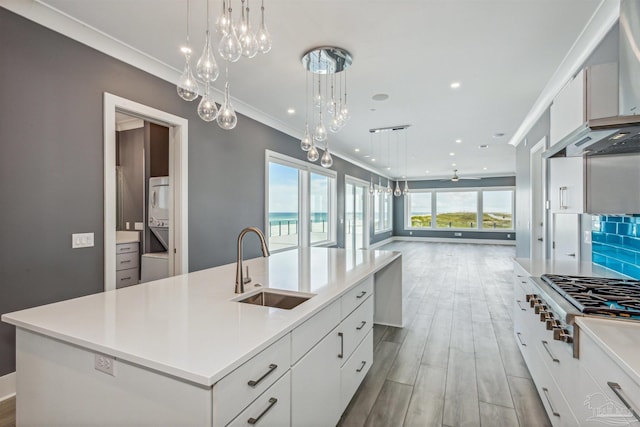 kitchen featuring sink, hanging light fixtures, stacked washer / dryer, a large island, and white cabinets