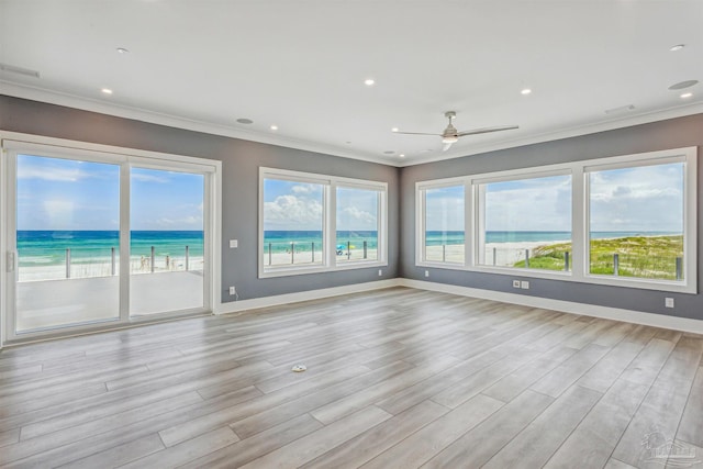 spare room featuring crown molding, light hardwood / wood-style flooring, a healthy amount of sunlight, and a water view