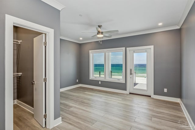 empty room with crown molding, ceiling fan, and light hardwood / wood-style flooring