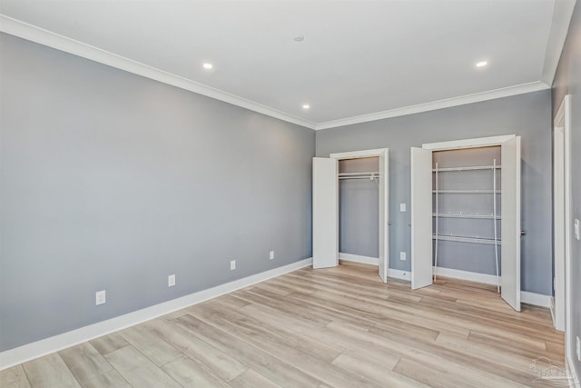 unfurnished bedroom with crown molding, light hardwood / wood-style flooring, and multiple closets