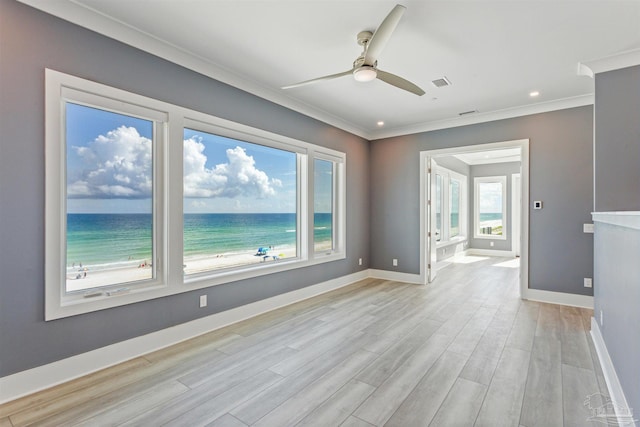 unfurnished room featuring a water view, ornamental molding, a view of the beach, and light hardwood / wood-style flooring