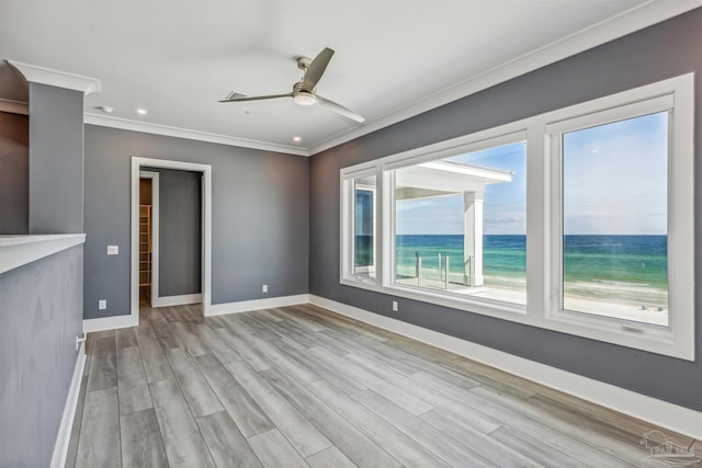 unfurnished living room featuring crown molding, a water view, ceiling fan, and light hardwood / wood-style flooring