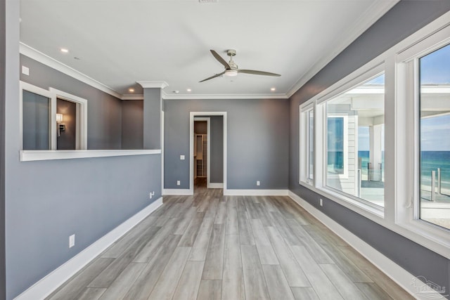 empty room featuring ornamental molding, light hardwood / wood-style floors, ceiling fan, and a water view