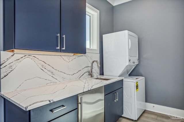 washroom featuring cabinets, hardwood / wood-style flooring, stacked washer / drying machine, and sink