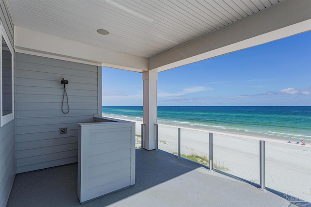 exterior space with a water view, a balcony, and a view of the beach