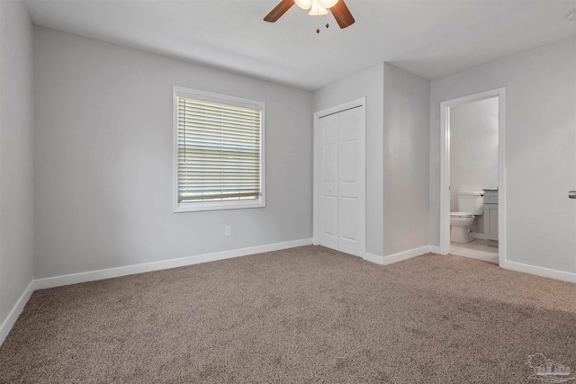 unfurnished bedroom with ceiling fan, a closet, connected bathroom, and carpet flooring