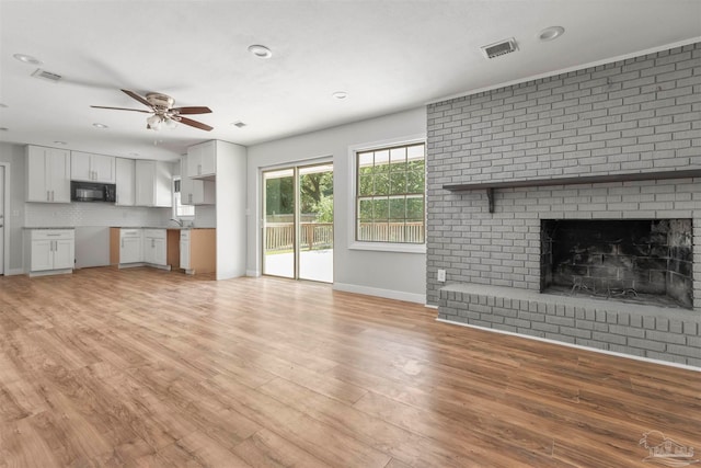 unfurnished living room featuring a fireplace, ceiling fan, and light hardwood / wood-style floors