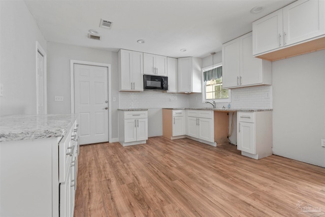 kitchen featuring white cabinets, sink, light hardwood / wood-style floors, and tasteful backsplash