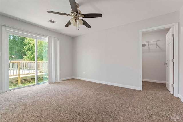 unfurnished bedroom featuring a walk in closet, carpet flooring, ceiling fan, a closet, and access to outside