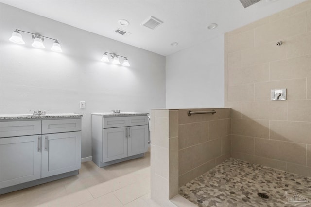 bathroom featuring tile patterned flooring, tiled shower, and vanity