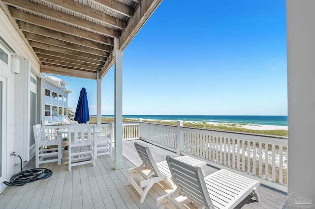 wooden deck featuring a water view and a beach view