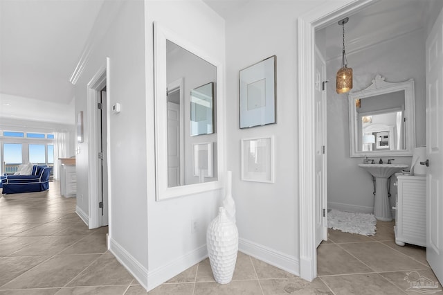 hall featuring light tile patterned floors and ornamental molding