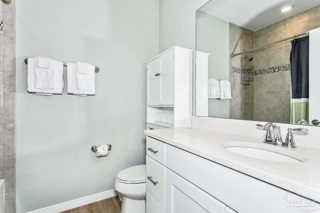 14390 Cordgrass Ln, Pensacola, FL 32507 - bathroom featuring toilet, wood finished floors, a tile shower, baseboards, and vanity