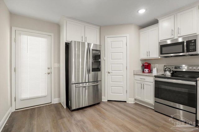 kitchen featuring stainless steel appliances, light hardwood / wood-style floors, and white cabinets