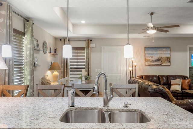 kitchen with sink, decorative light fixtures, and light stone countertops