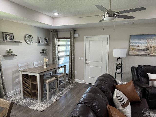 living room with ceiling fan, dark hardwood / wood-style floors, and a textured ceiling