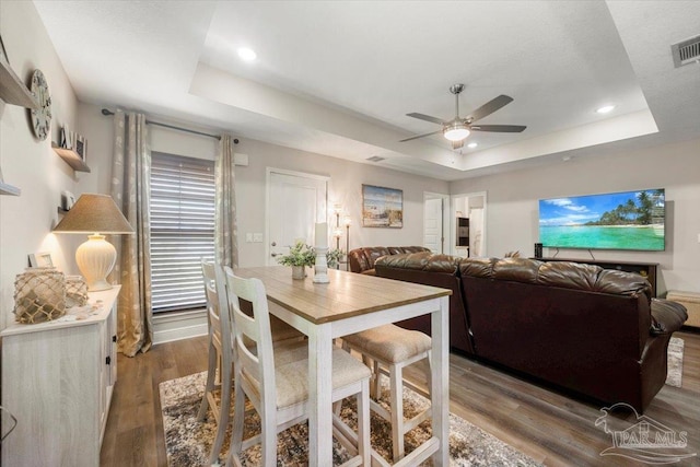 dining room featuring a tray ceiling, wood-type flooring, and ceiling fan