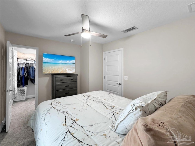 bedroom with ceiling fan, carpet, a textured ceiling, a spacious closet, and a closet