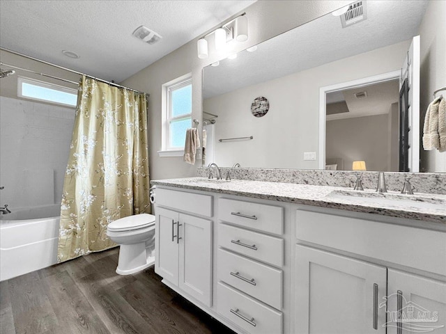 full bathroom featuring wood-type flooring, plenty of natural light, vanity, and a textured ceiling