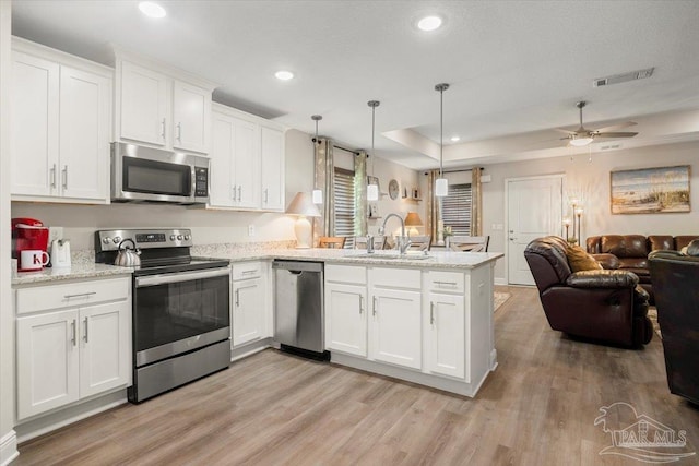 kitchen featuring pendant lighting, sink, white cabinets, kitchen peninsula, and stainless steel appliances