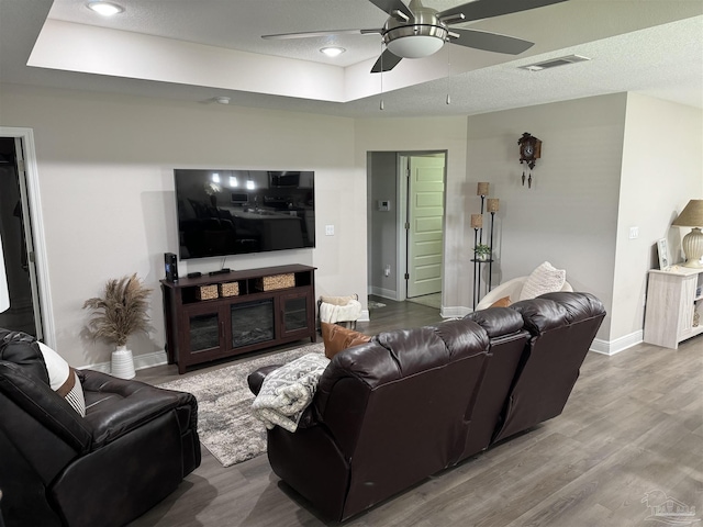 living room featuring a raised ceiling, hardwood / wood-style flooring, and ceiling fan