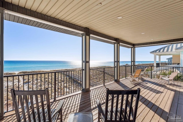 wooden deck with a water view and a beach view