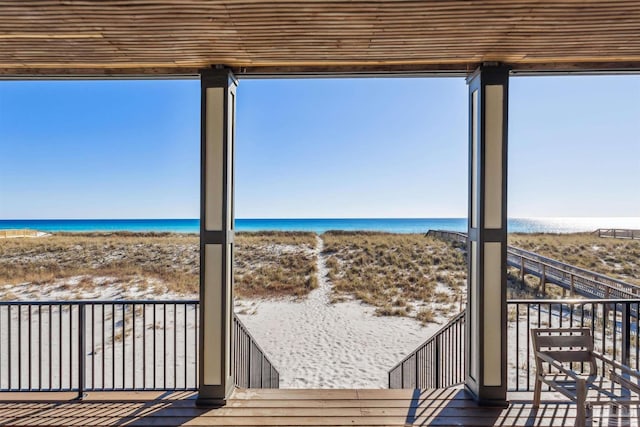 wooden deck featuring a water view and a beach view