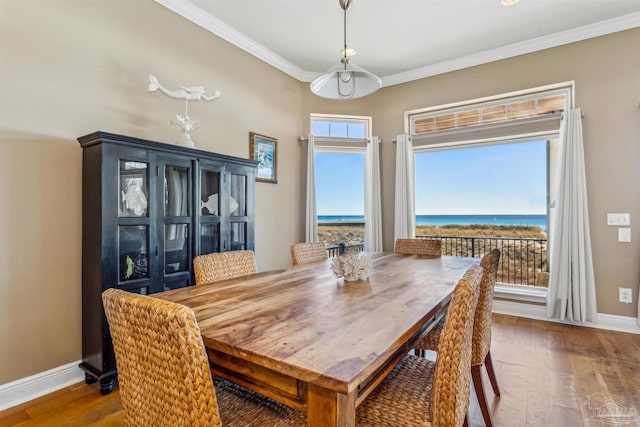 dining room featuring hardwood / wood-style floors, a water view, and ornamental molding