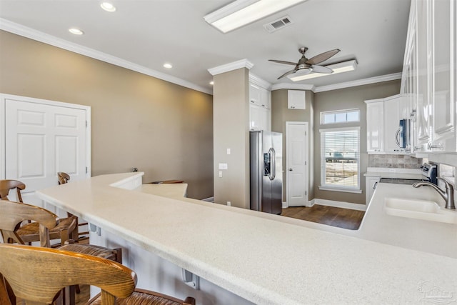 kitchen with kitchen peninsula, appliances with stainless steel finishes, ceiling fan, sink, and white cabinetry