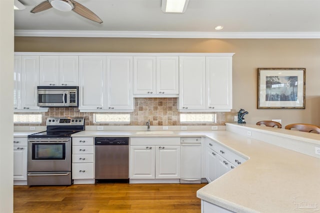 kitchen with white cabinetry, sink, backsplash, crown molding, and appliances with stainless steel finishes