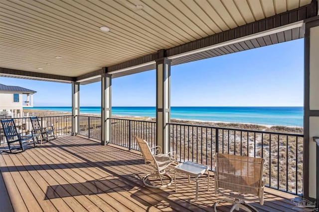 wooden terrace with a water view and a view of the beach