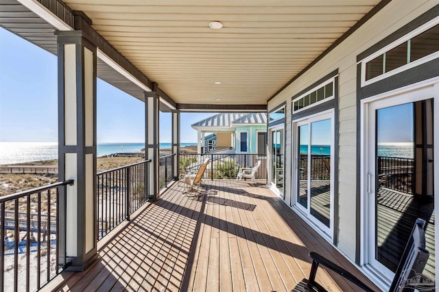 wooden deck featuring a water view and a view of the beach