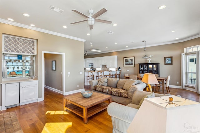 living room with hardwood / wood-style flooring, ceiling fan, and crown molding