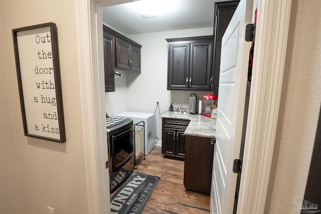 kitchen with light stone countertops, washer and dryer, sink, and dark hardwood / wood-style floors