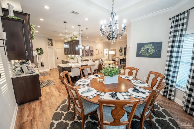 dining space with ornamental molding, sink, light hardwood / wood-style flooring, and a notable chandelier