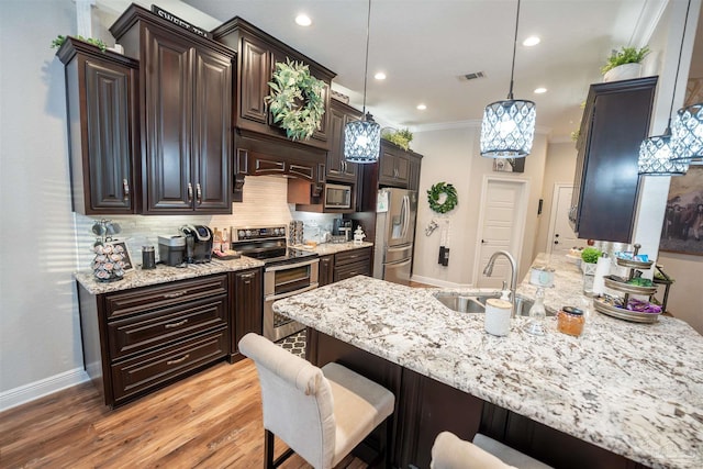 kitchen featuring sink, a breakfast bar area, crown molding, pendant lighting, and stainless steel appliances