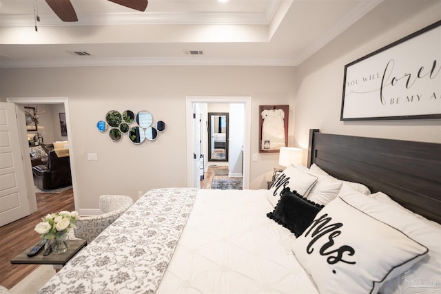 bedroom with ceiling fan, ornamental molding, wood-type flooring, and a tray ceiling