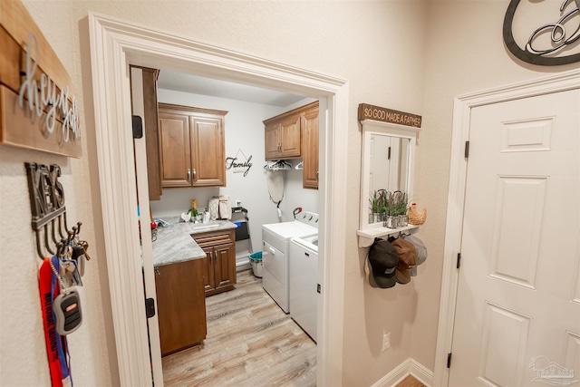 laundry area with separate washer and dryer, light hardwood / wood-style flooring, and cabinets