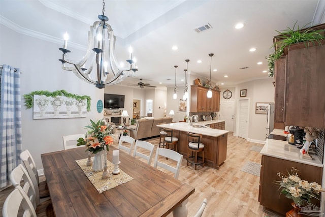 dining area featuring ornamental molding, sink, ceiling fan with notable chandelier, and light hardwood / wood-style floors