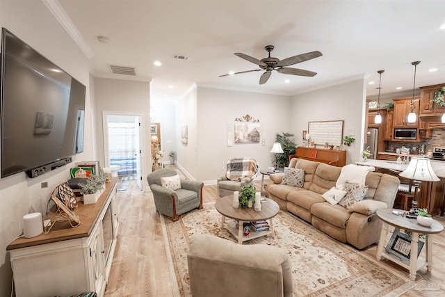 living room featuring crown molding, ceiling fan, and light wood-type flooring