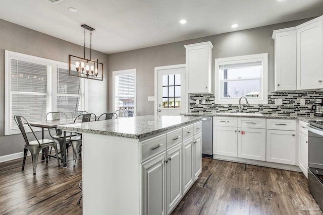 kitchen with sink, white cabinets, a kitchen island, decorative light fixtures, and stainless steel dishwasher