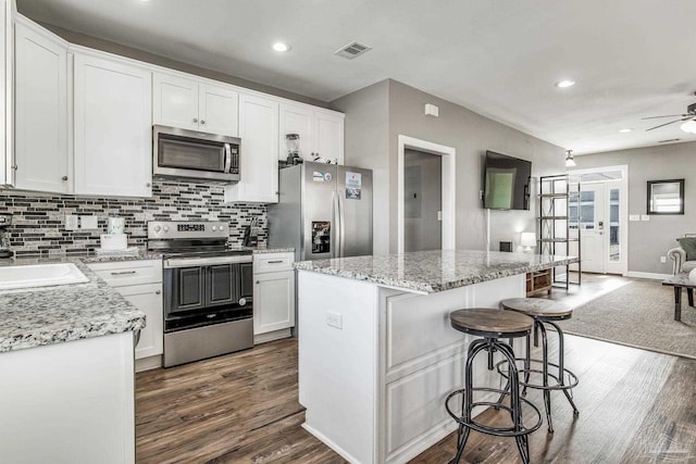 kitchen featuring a breakfast bar, dark hardwood / wood-style flooring, a kitchen island, stainless steel appliances, and white cabinets