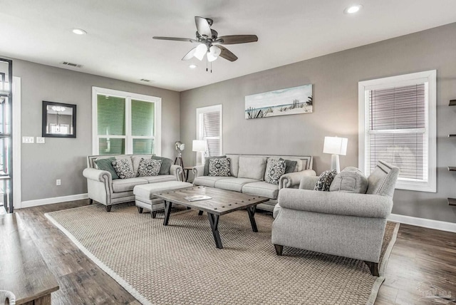living room with dark wood-type flooring, ceiling fan, and plenty of natural light