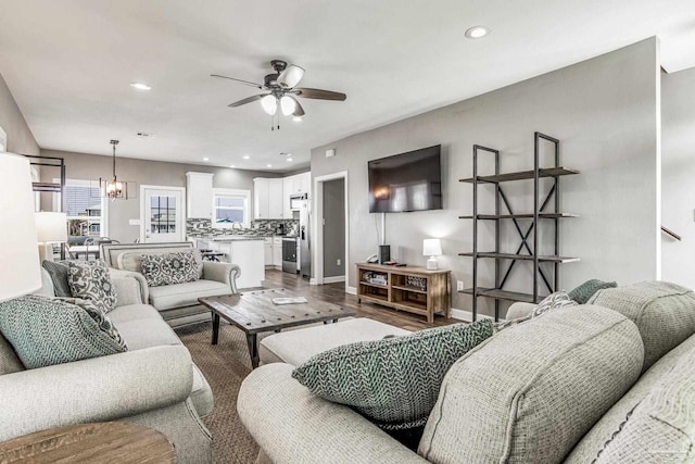 living room featuring ceiling fan with notable chandelier and wood-type flooring