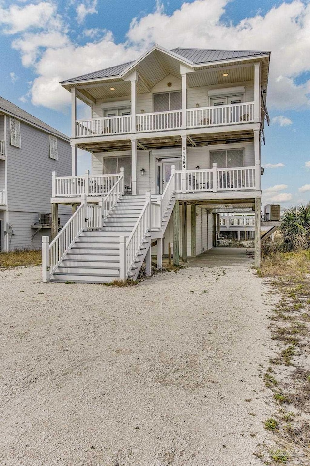 beach home featuring cooling unit, a carport, and a balcony