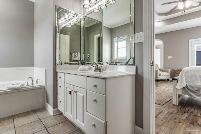 bathroom with a tub to relax in, vanity, ornamental molding, ceiling fan, and tile patterned floors