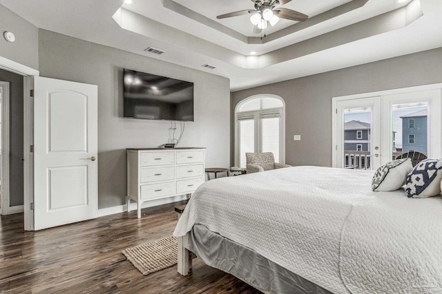 bedroom featuring dark hardwood / wood-style floors, access to outside, ceiling fan, a raised ceiling, and french doors