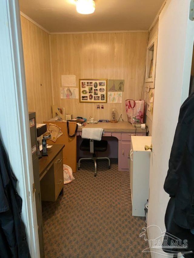 office area with dark carpet, crown molding, and wood walls